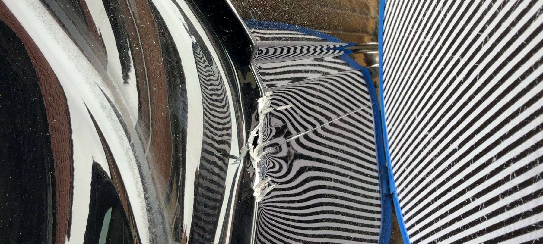 Türkante einer schwarzen Limousine im Streifenlicht, die Verformung zeichnet sich als Welle ab — Akte mit 15.341,81 Euro Schadenhöhe
